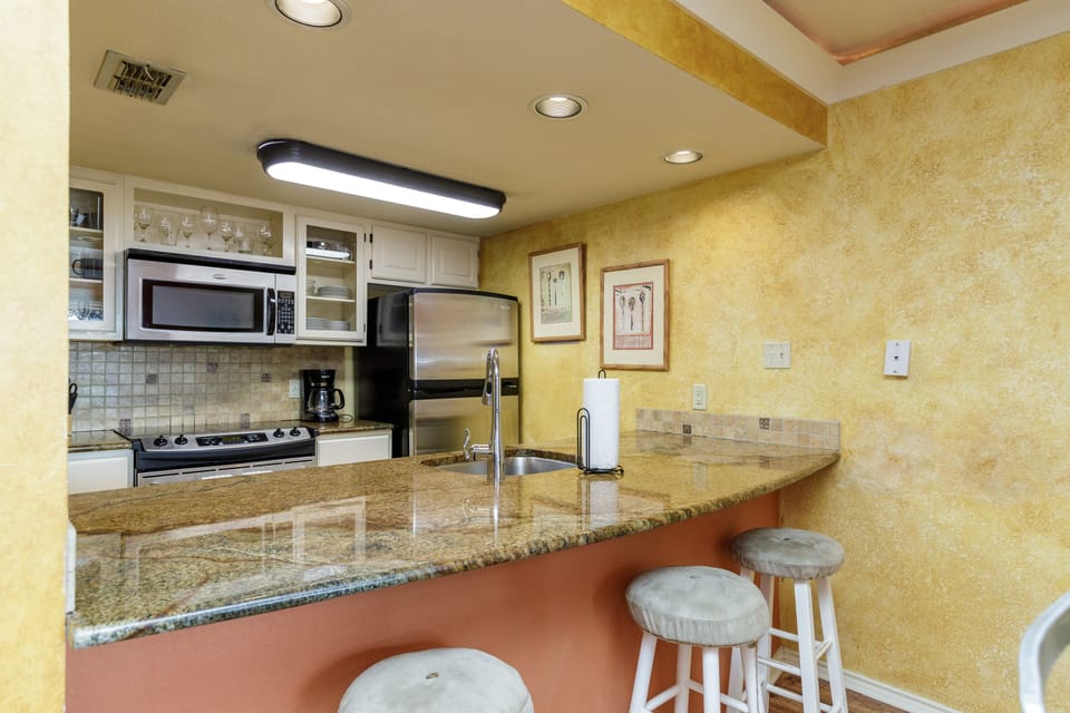 Your fully equipped kitchen features granite countertops, stainless steel appliances, and a convenient breakfast bar where you can enjoy morning coffee.