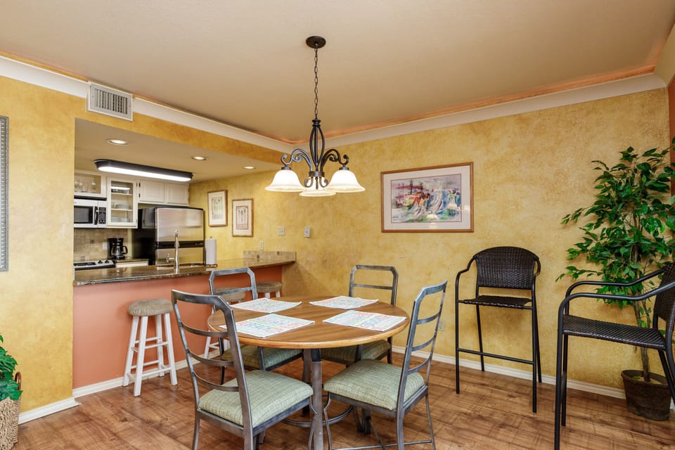 Gather around your welcoming dining table where warm lighting and open kitchen create perfect moments for shared meals and conversation.