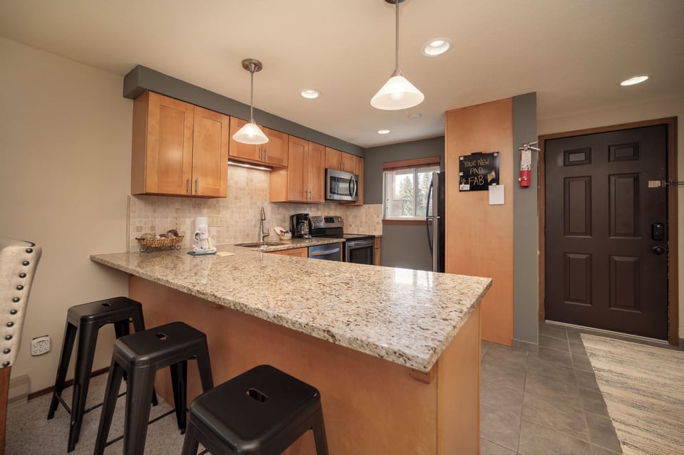 Cook together at your spacious granite breakfast bar with modern appliances and warm wood cabinetry creating the perfect gathering spot.