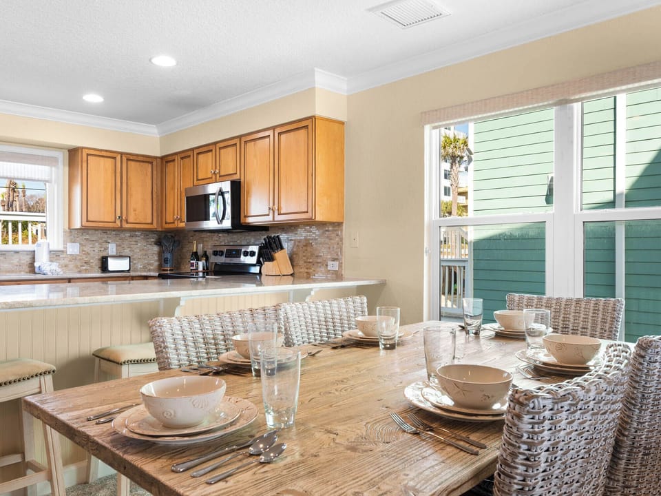 The bright kitchen and dining space awaits, perfectly set for memorable meals with warm wood tones and charming wicker seating.