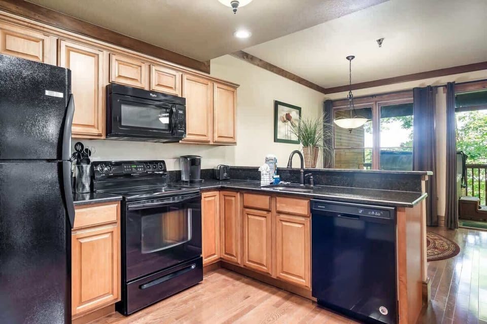 The sleek black appliances pop against the warm wood paneling, creating a space that's both inviting and stylish. Cooking here feels like a true delight.