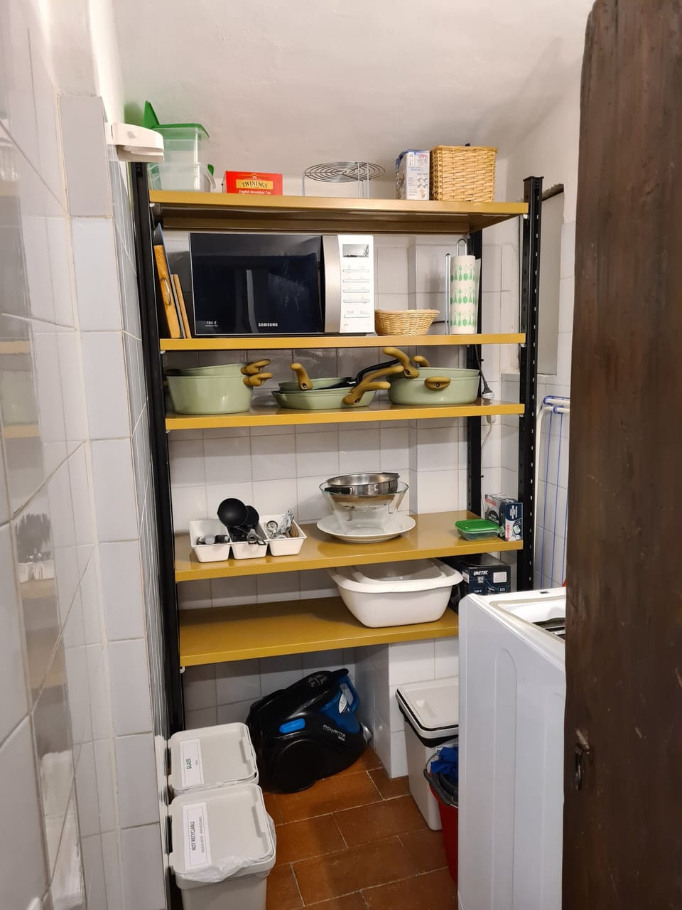 The closet at the right of the kitchen wall, with laundry machine and microwave.