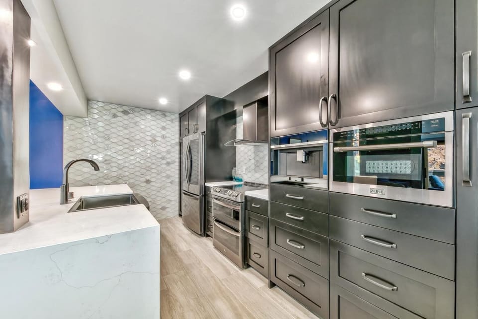 Sleek modern kitchen with marble counters, stainless appliances, and stylish backsplash awaits your culinary adventures.