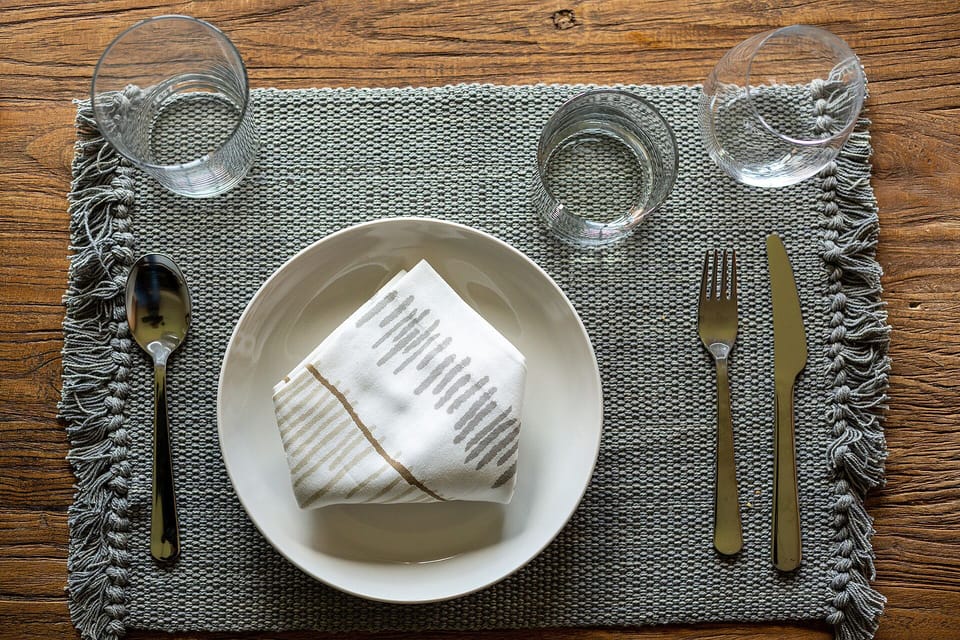 Your elegant dining setup awaits with thoughtfully arranged place settings on rich wooden surfaces, perfect for memorable meals during your stay.