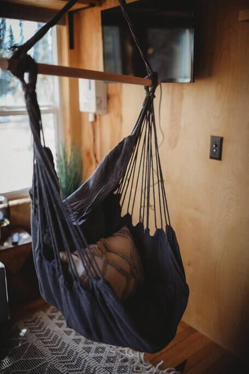 Relax in the cozy hammock chair inside the treehouse, a perfect spot to unwind with a view of the scenic surroundings