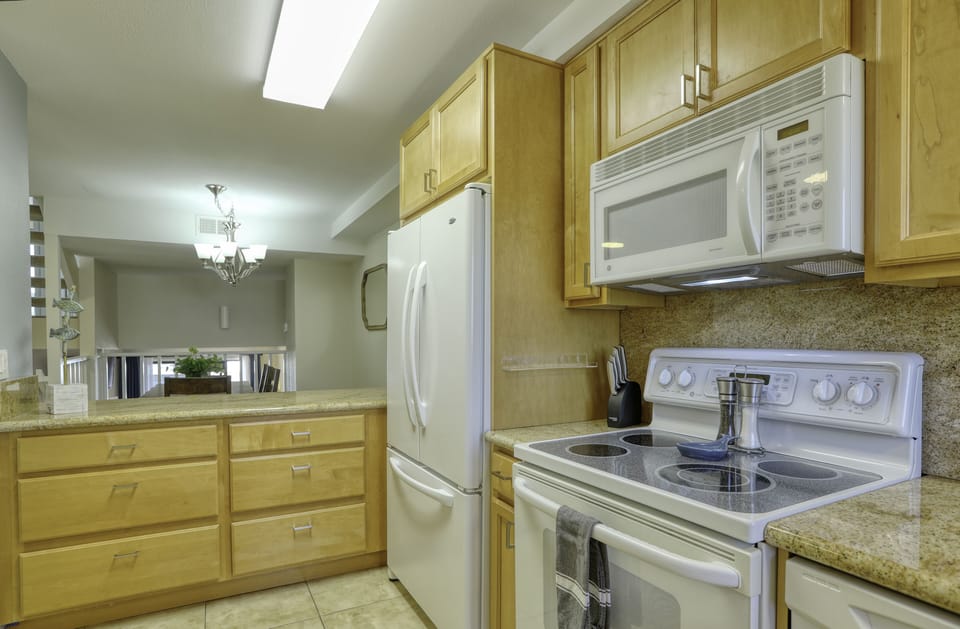 A modern electric range, large microwave and oversized refrigerator/freezer accommodate family dining and leftovers.