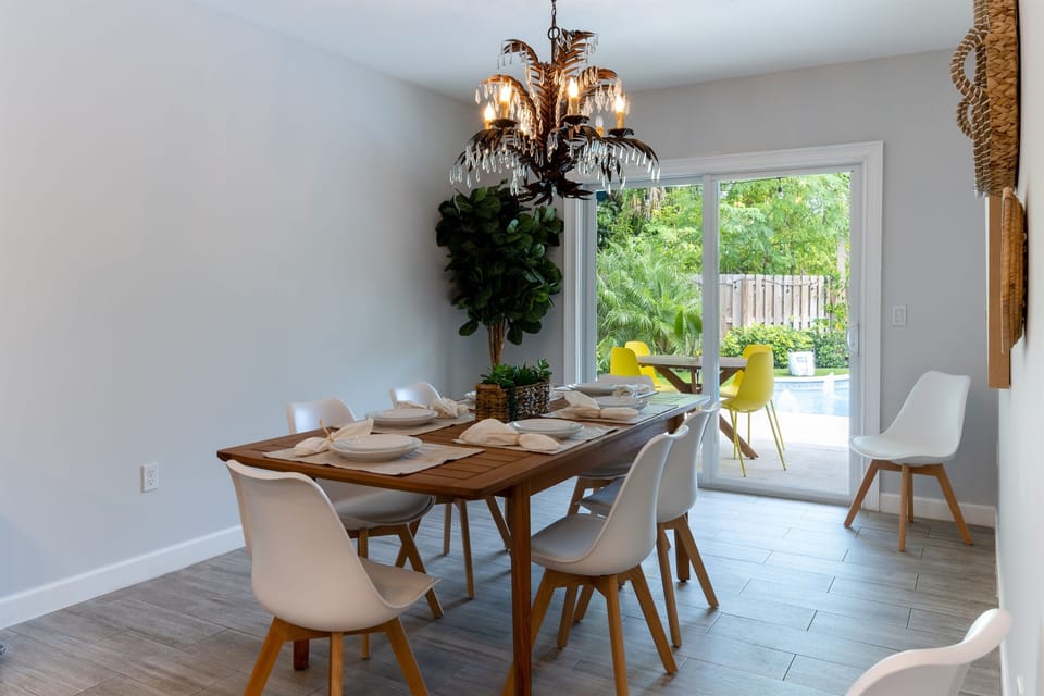 The Dining table is just off the kitchen for easy service. It is a rectangular wooden table that seats 6 with lovely woven basket wall décor and a unique palm leaf crystal chandelier above the table.