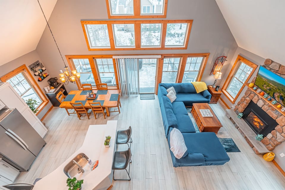 Soak in the warmth of this stunning great room—cathedral ceilings, expansive windows, and cozy fireside vibes made for unforgettable moments.