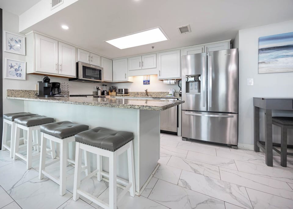 Modern kitchen features granite countertops, modern stainless appliances, and a breakfast bar with stylish seating