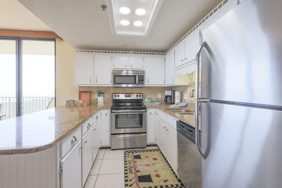Kitchen features a breakfast bar, stainless appliances, and granite countertops, with a view of the beach