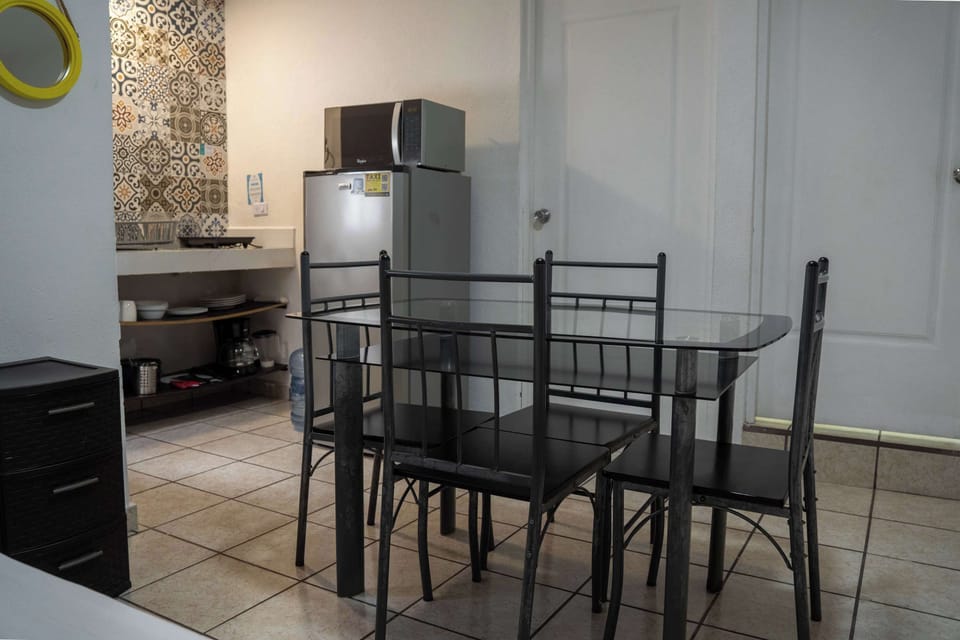 Bright dining nook with a glass table and full fridge over patterned tile, ready for easy meals
