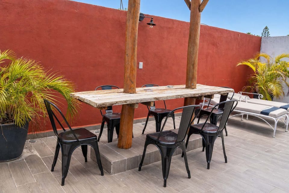 Shared rooftop terrace with a long communal table and warm accent wall, a breezy place to gather in downtown Cancun