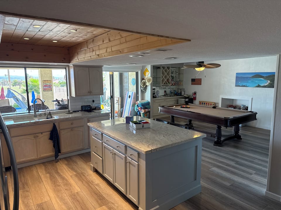 Remodeled kitchen w/granite countertops, island, Kohler sink, game room behind.