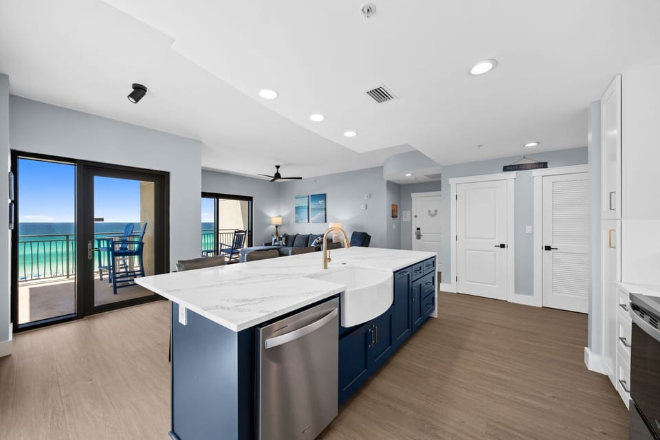 Your modern kitchen island flows seamlessly into the living space, where stunning ocean views through floor-to-ceiling windows create the perfect backdrop for cooking and entertaining.