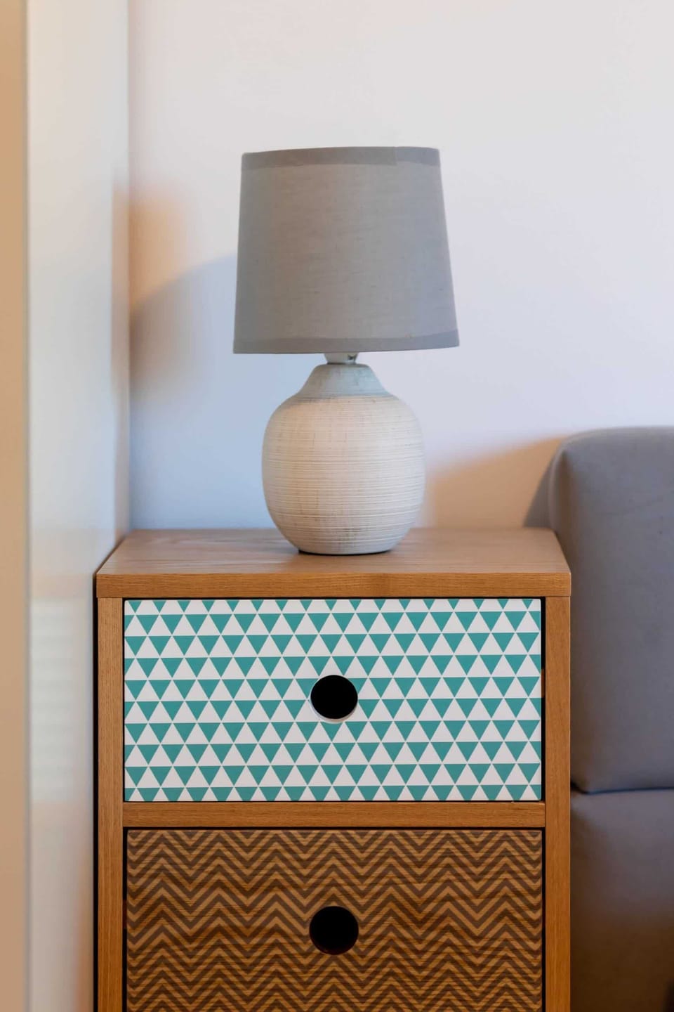 The nightstand next to the bed features a modern design with a lamp and a small storage compartment for essentials, creating a functional and stylish piece of furniture.