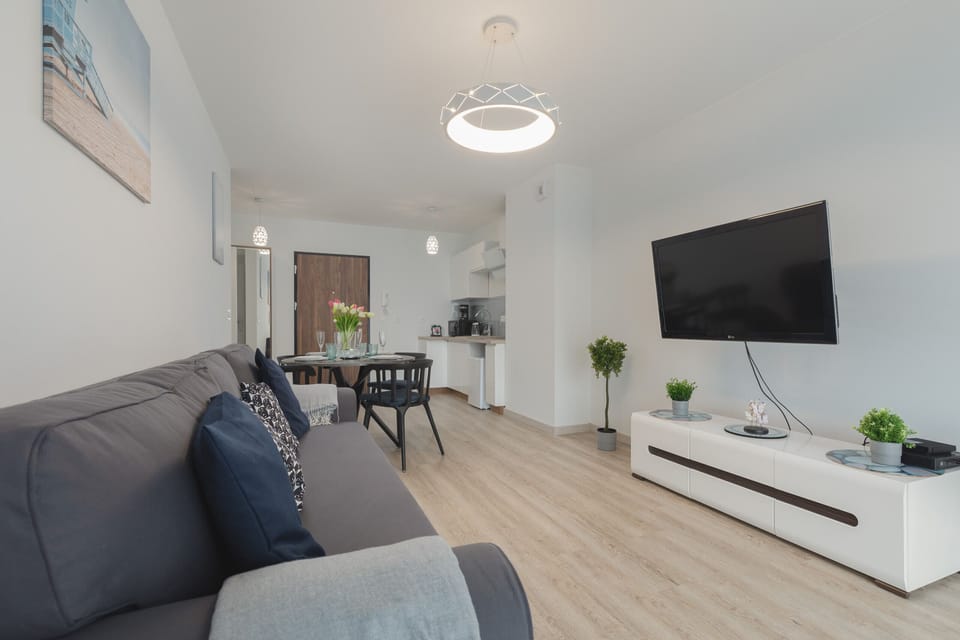 A living room with a large gray sofa, TV, and light decor. Perfect for relaxing in a bright, modern space.