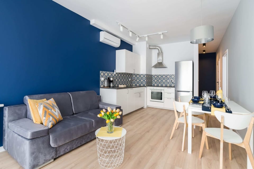 Stylish living room with a sofa bed, TV and kitchenette with dining area.