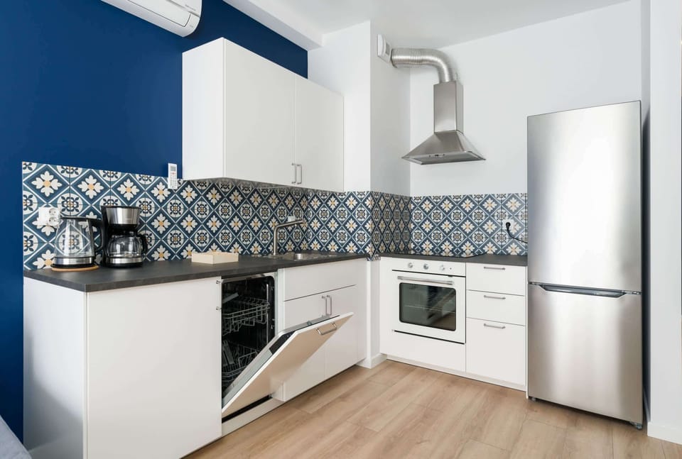 Kitchenette with induction hob, oven, fridge, freezer, electric kettle, coffee maker and dishwasher.