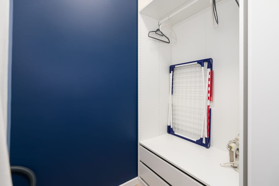 Closet with hangers, shelves, mirror and iron.