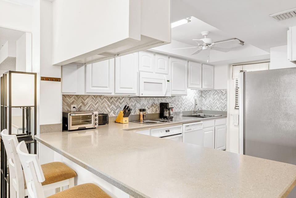 Modern kitchen with sleek white cabinets and stylish backsplash.