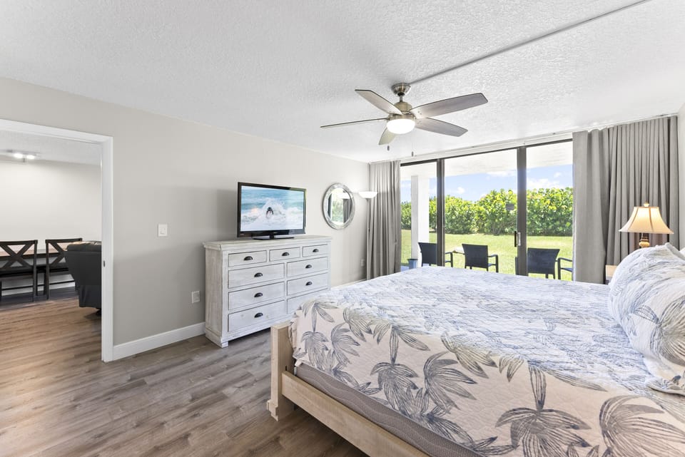 Luxurious master bedroom featuring a king bed, TV, and patio access