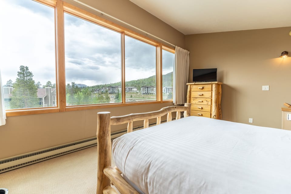 Upstairs bedroom featuring a queen bed, private bathroom, and scenic views from the windows.