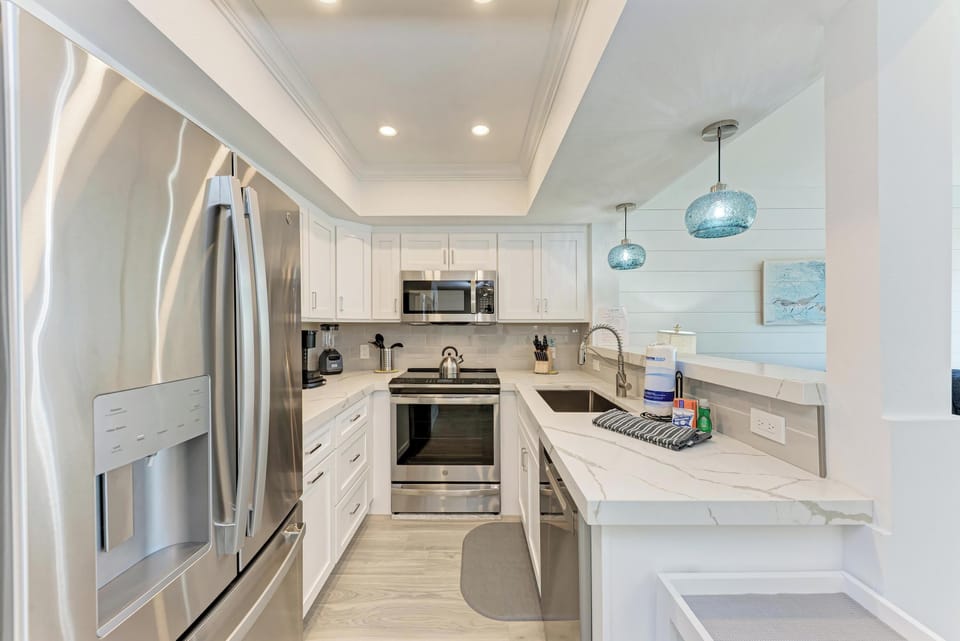 Your fully equipped modern kitchen awaits with sleek white cabinets, marble countertops, and premium stainless steel appliances for memorable meal preparation.