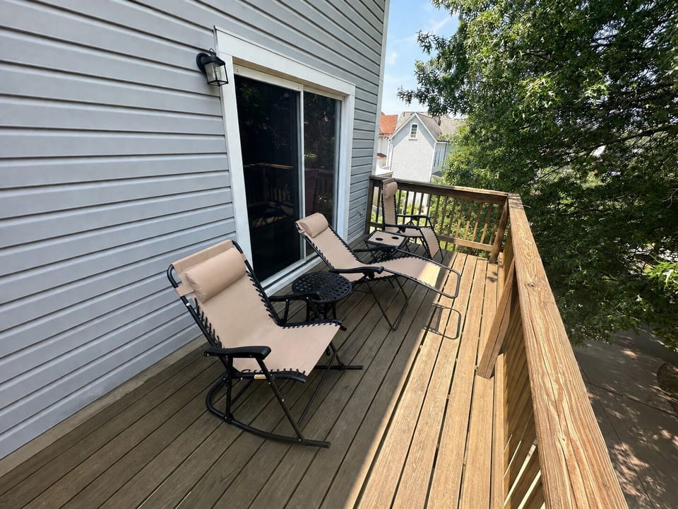 A rocker, 2 comfortable zero-gravity chairs, and tables are on the deck