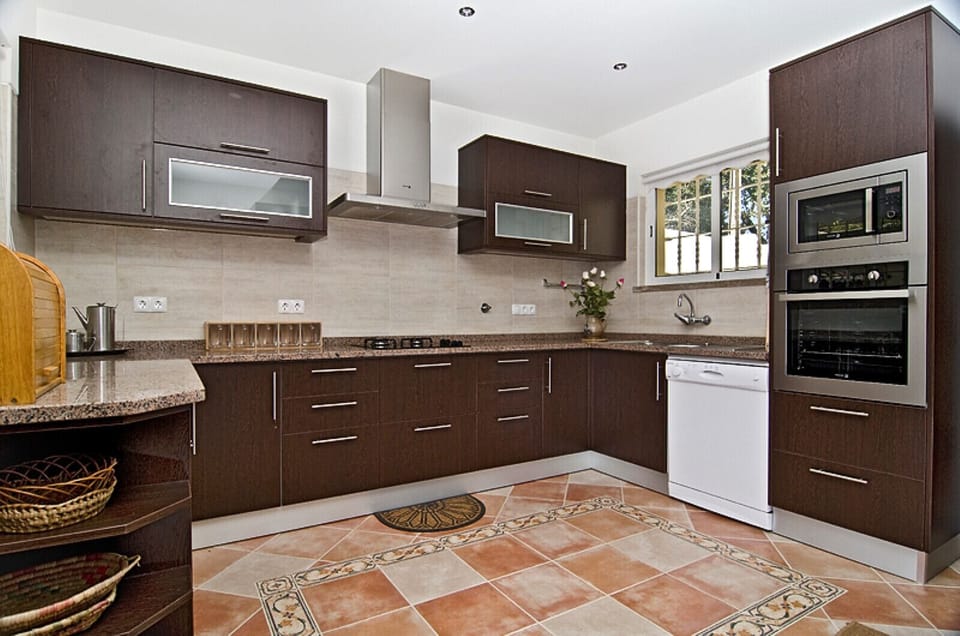 The large kitchen in dark wood look in Villa Lorena is equipped with modern kitchen appliances: there is a gas cooker, dishwasher as well as oven and microwave.