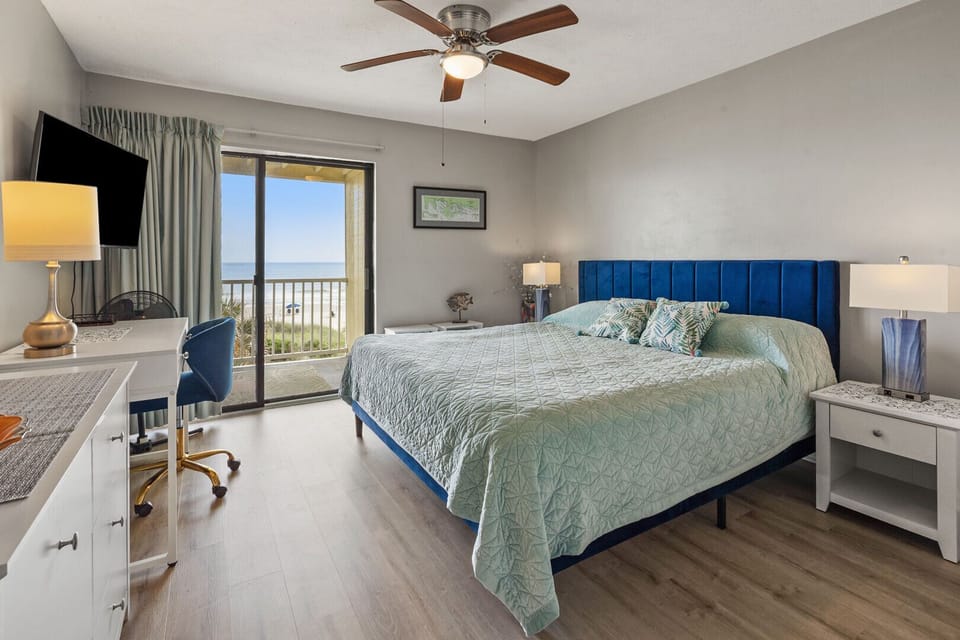 Bedroom with blue headboard and sliding doors to the ocean view balcony at Windy Shores II 201, Windy Hill