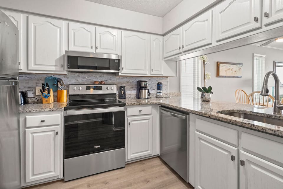 Kitchen with white cabinetry, gray counters and a range at Windy Shores II 201, a 3-bedroom Windy Hill rental