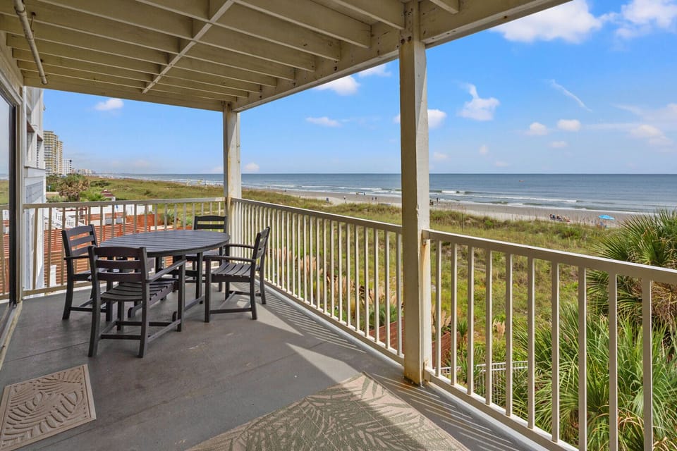 Shaded oceanfront porch with a table for four at Windy Shores II 201, a 3-bedroom Windy Hill condo