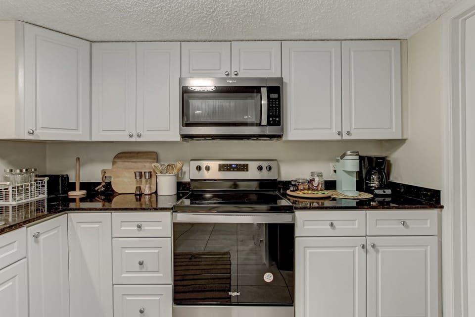 Fully Equipped Kitchen with Granite Countertops, Stainless Steel Appliances, and White Cabinetry