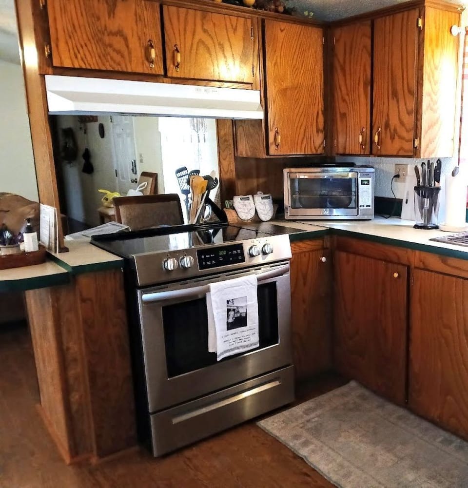 Kitchen peninsula showing 4-burner electric stove, oven & counter seating