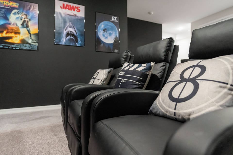 Relax in plush black recliners amid vibrant movie posters that create a fun atmosphere. The soft carpet adds to the comfort, making this the ideal spot for movie nights or cozy gatherings with friends.