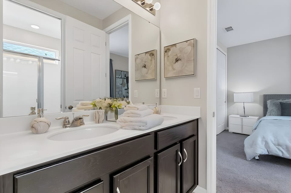 Enjoy a beautifully designed bathroom featuring a sleek white countertop and dark wood cabinetry for ample storage. Natural light brightens the contemporary decor and plush towels, offering a refreshing start to your day.