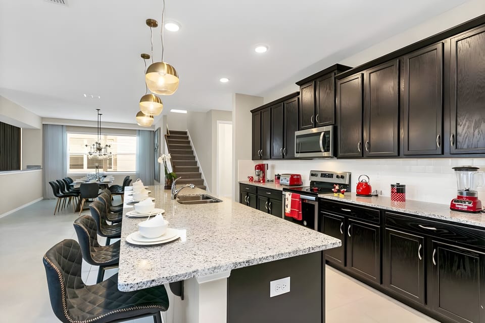 Step into a stylish kitchen featuring sleek black cabinetry and a striking granite island, perfect for gathering. The warm lighting creates a welcoming atmosphere, enhanced by cozy seating that invites conversation over a meal.