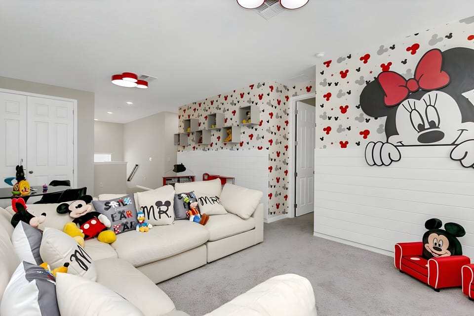 Enjoy a cheerful living room with playful Minnie Mouse accents and colorful throw pillows that encourage relaxation. The spacious white sectional offers a cozy spot to unwind, while the light, airy ambiance enhances your stay.