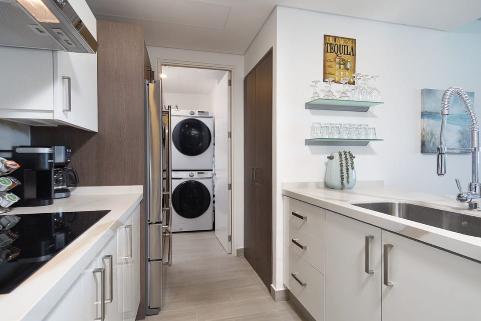 The washer and dryer are in the utility room beyond the kitchen.