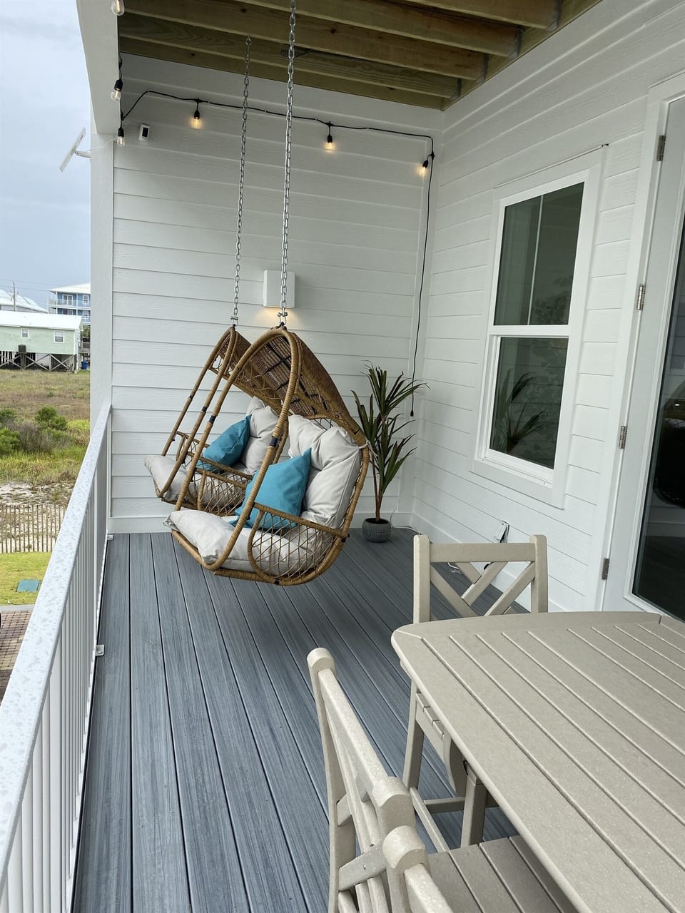 Main level veranda with 6 seat outdoor dining table and hanging basket chairs