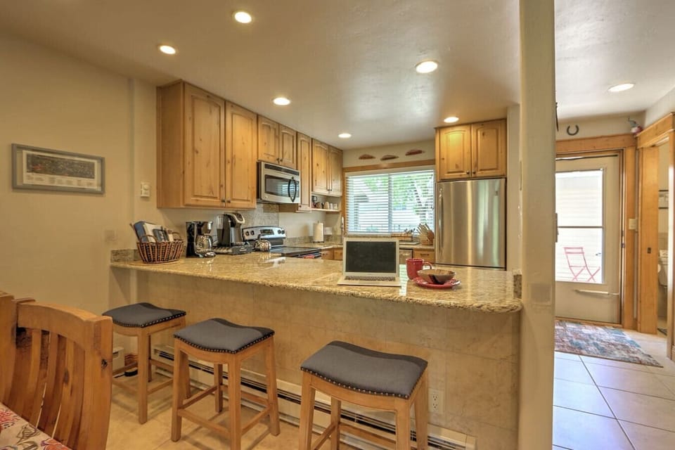 Breakfast bar seating, well-equipped kitchen, and front entrance to condo