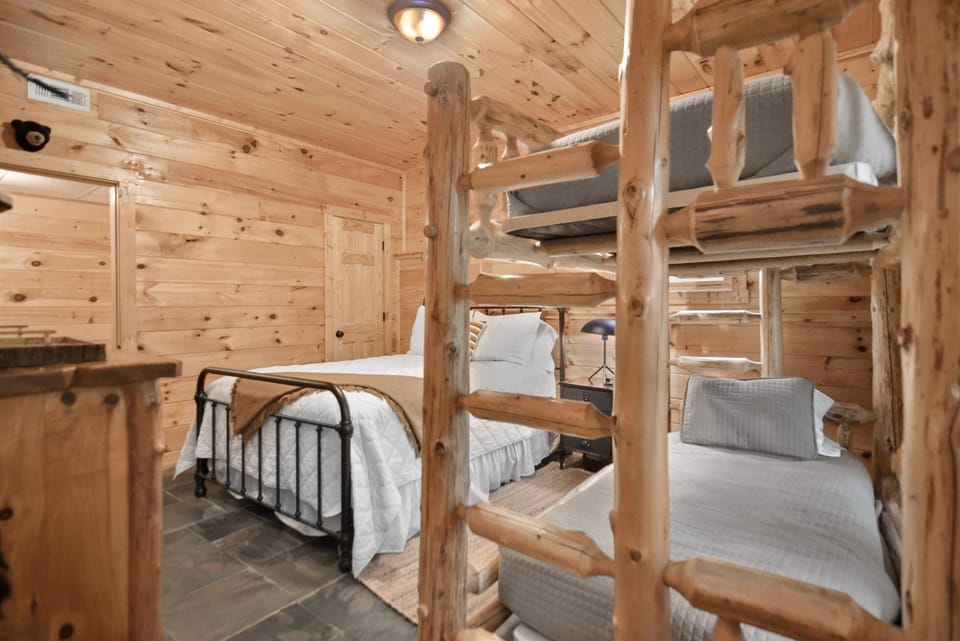 A bedroom in the lower level fit for a family that features a queen size bed and twin bunk beds.