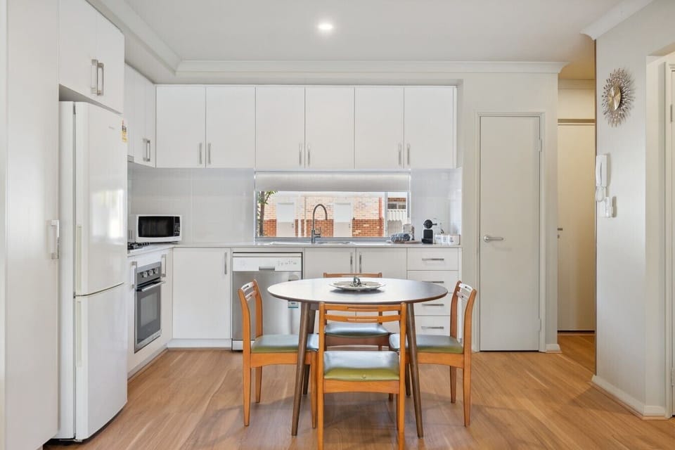 Gas cooktop, oven, dishwasher, and a round table with green vinyl chairs