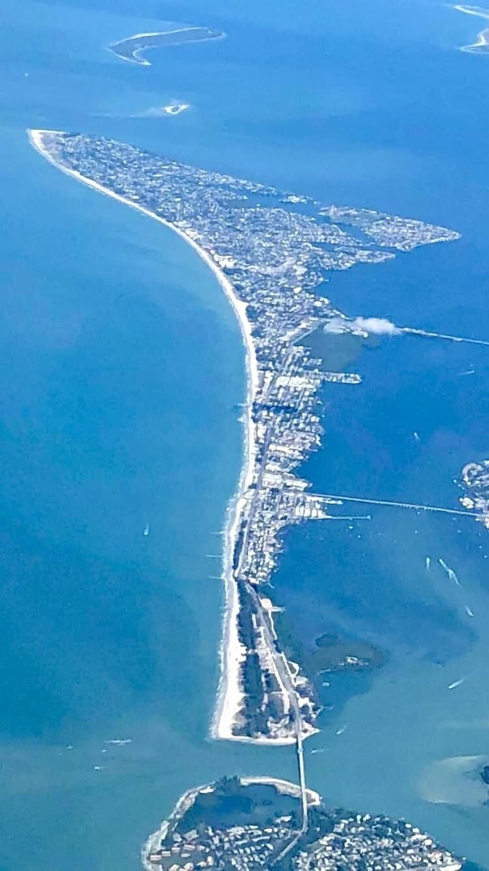 Aerial view of the coastline showing the long sandy beach, turquoise Gulf waters, and island community below