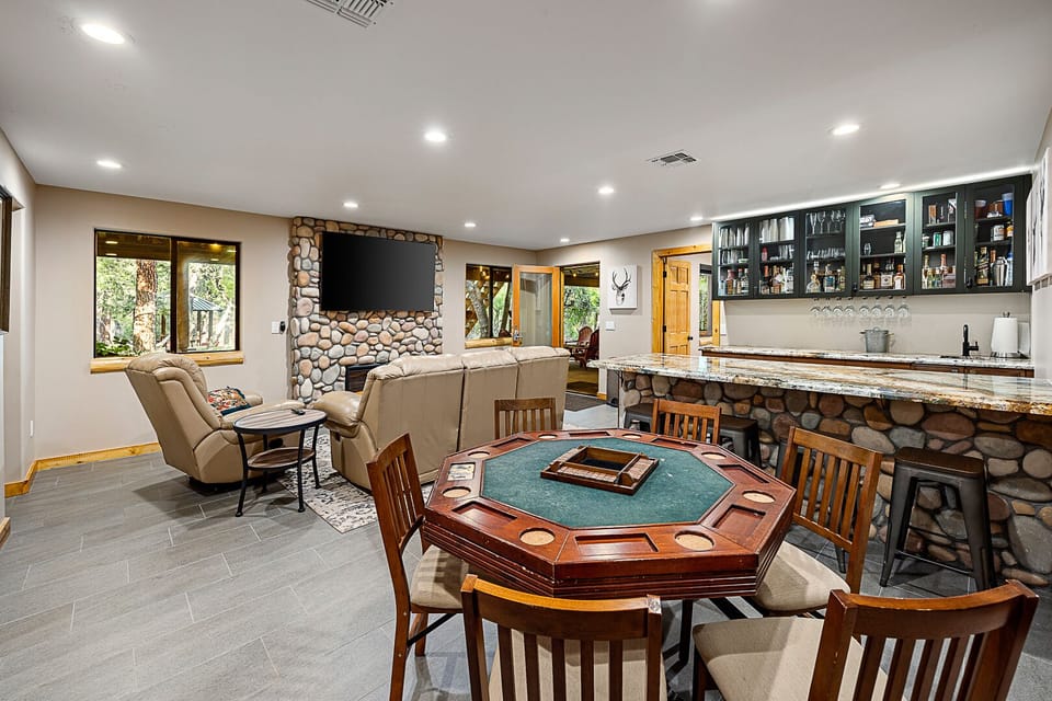 Cozy game room with stone bar, poker table, and large TV for movie nights.