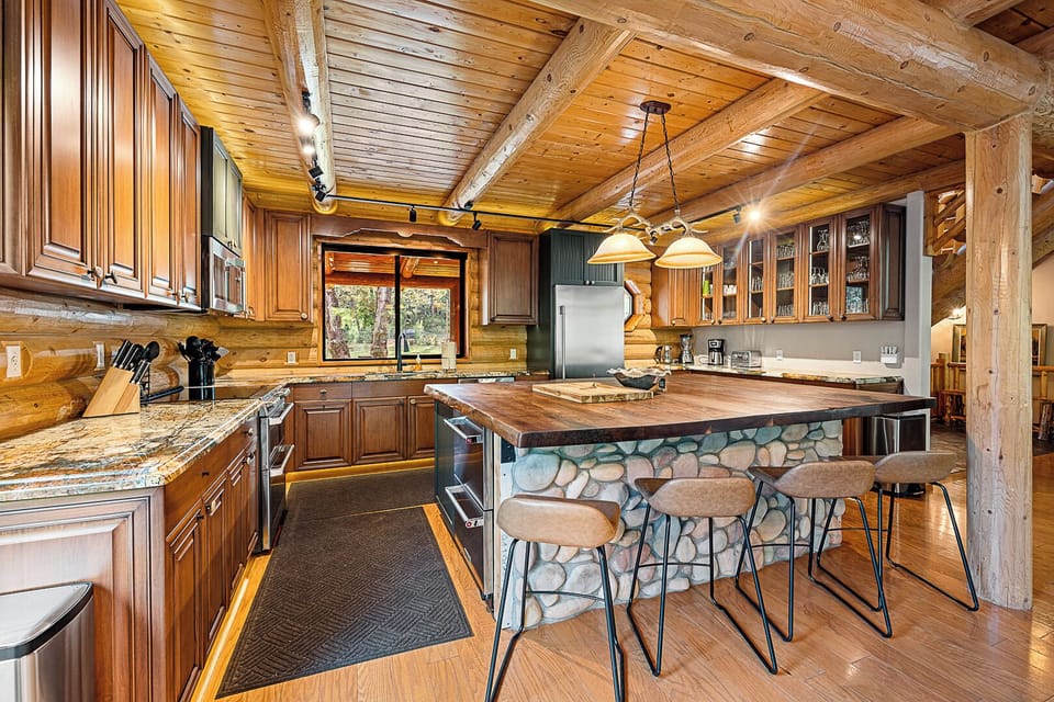 Gourmet log cabin kitchen with stone island, premium appliances, and charm.