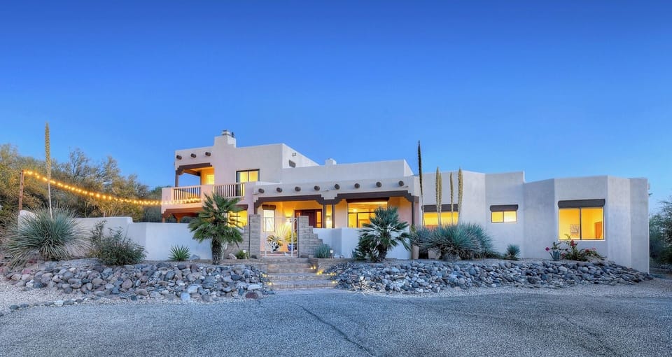 House as viewed from driveway with outdoor lights extending the living space.