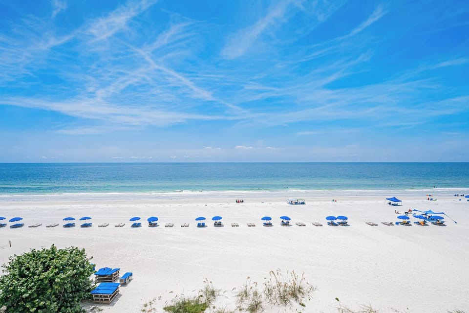 Pristine white-sand beach with gentle waves and vibrant blue skies creates an idyllic coastal setting for relaxation and seaside enjoyment.