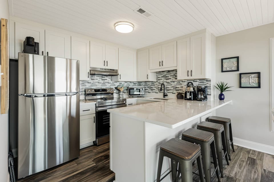 Large open well stocked kitchen with bar and stools