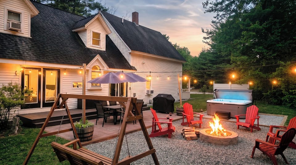 Cozy backyard oasis with hot tub, fire pit, and string-lit seating